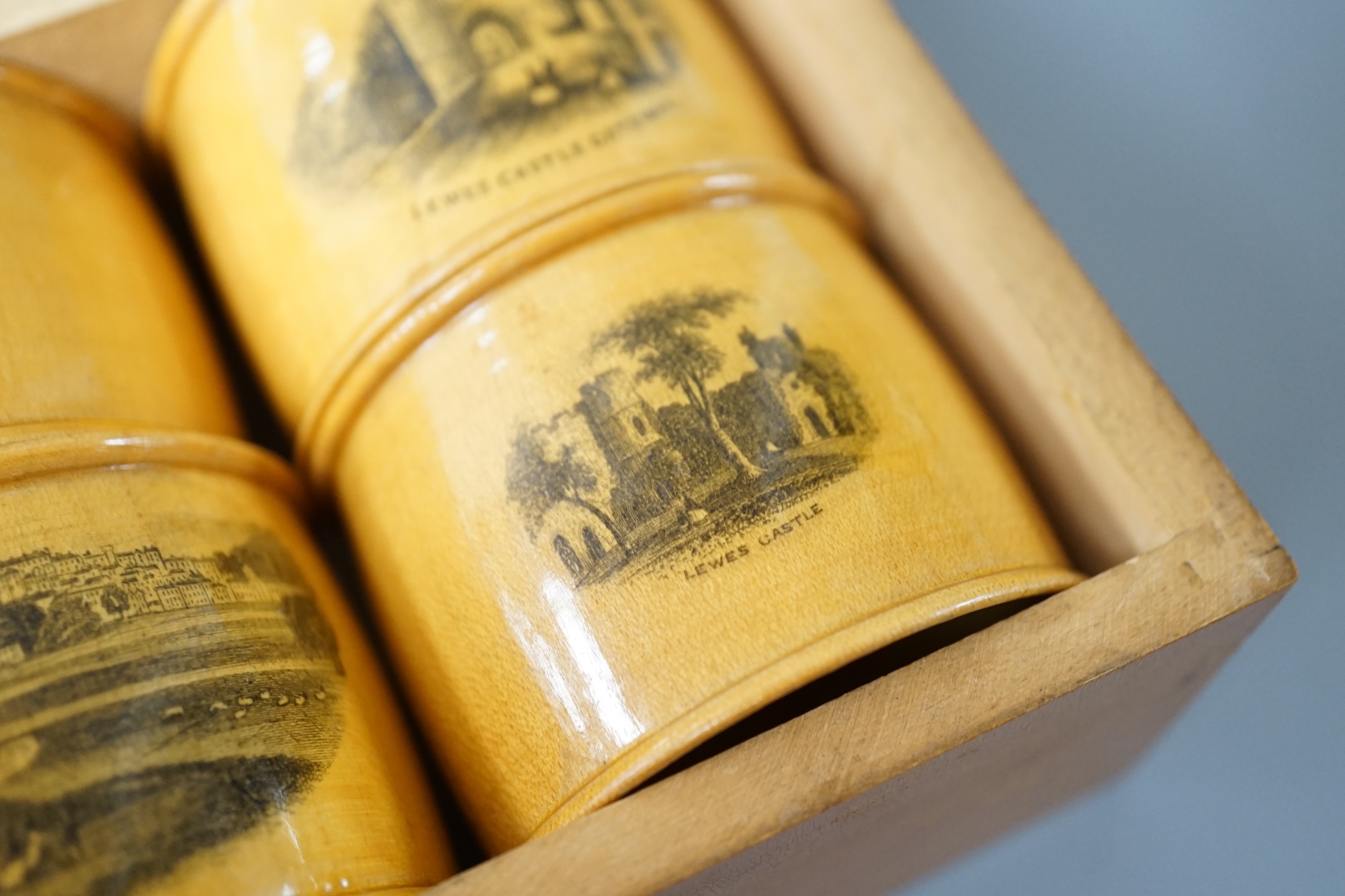 A set of 6 late 19th century mauchline ware napkin rings decorated with scenes of Lewes, housed in matching box. 18cm
